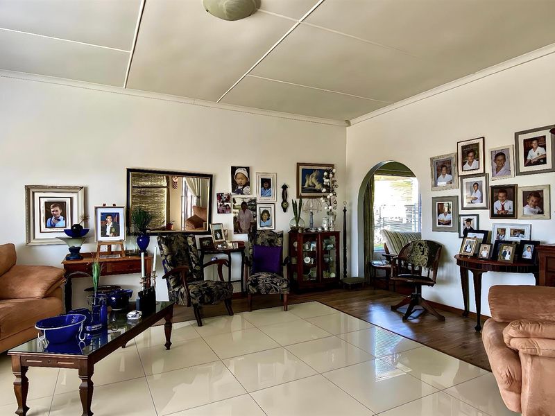 Spacious living room featuring tiled flooring, an arched doorway, and a neutral color palette, providing a comfortable and versatile area for relaxation.
