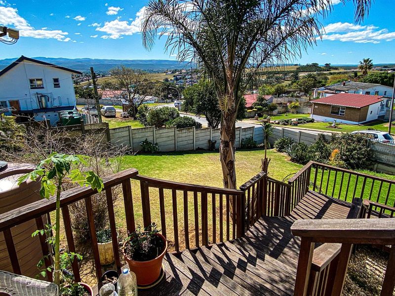Elevated wooden deck overlooking a private backyard with lawn, mature palm tree, and expansive suburban and mountain views.