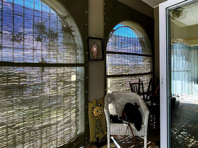 A covered patio area featuring arched openings with fitted privacy screens and tiled flooring, providing a sheltered outdoor transition space.