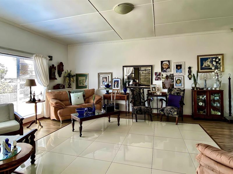 Spacious living room featuring large format floor tiles, neutral walls, and natural light through a large window.
