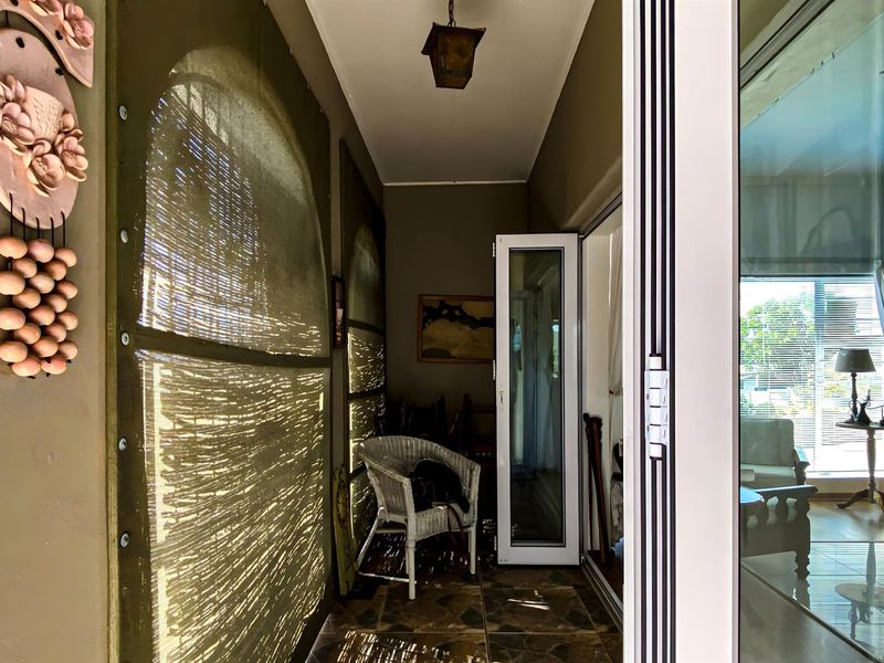 A covered patio area featuring tiled flooring, a hanging light fixture, and access to the interior living space through glass doors.