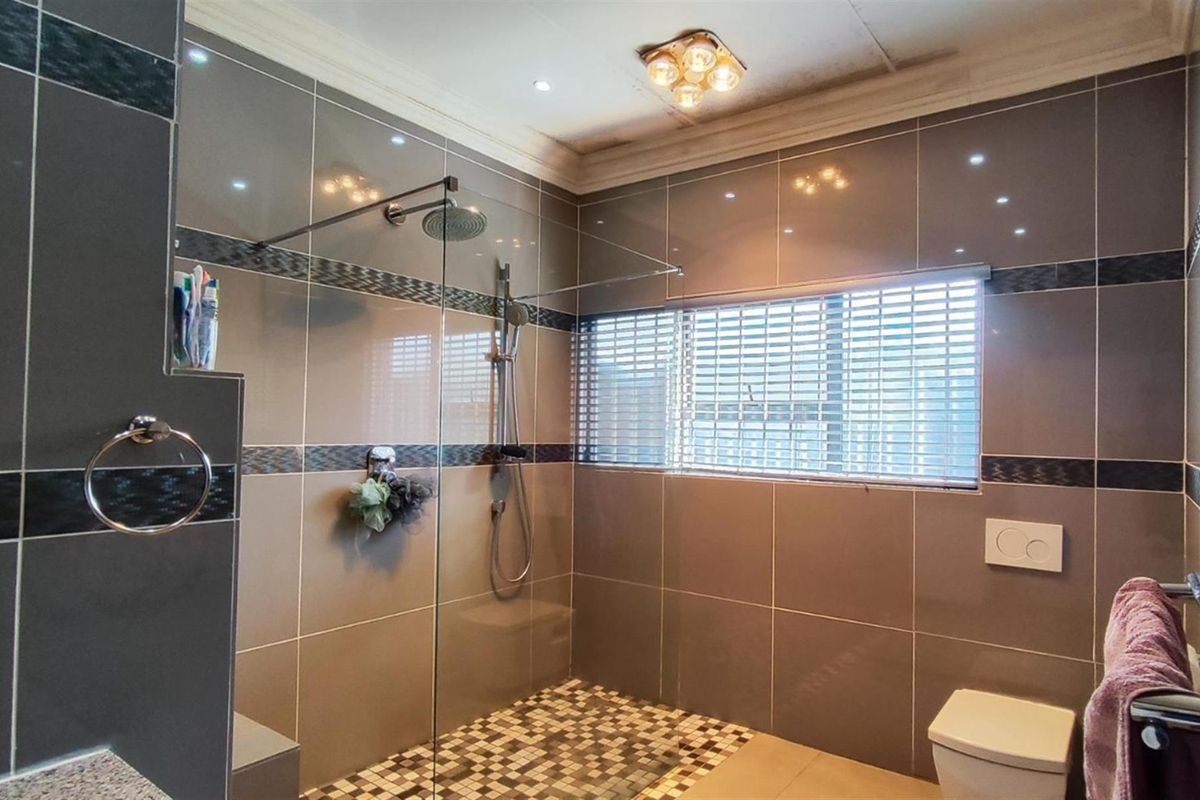 Modern bathroom featuring a spacious walk-in shower with glass screen, mosaic floor tiling, and contemporary wall tiles.