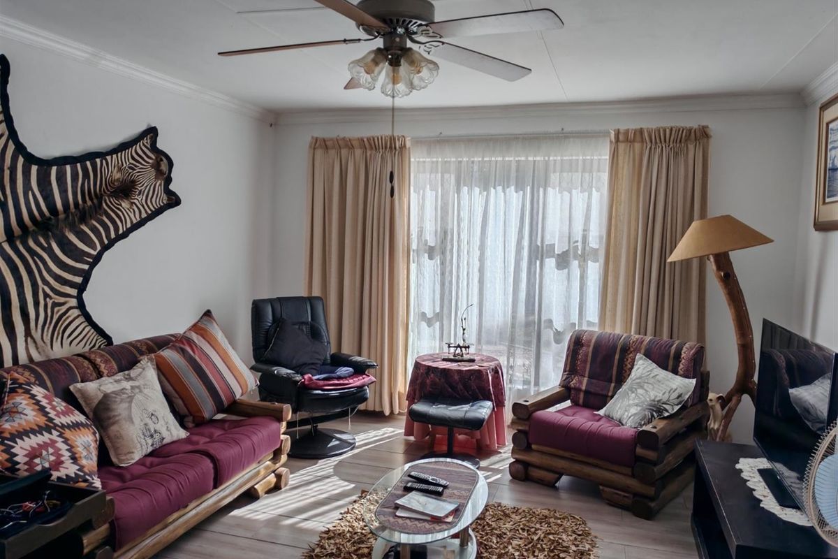A comfortable living room featuring tiled flooring, a ceiling fan, and large sliding glass doors that provide natural light.