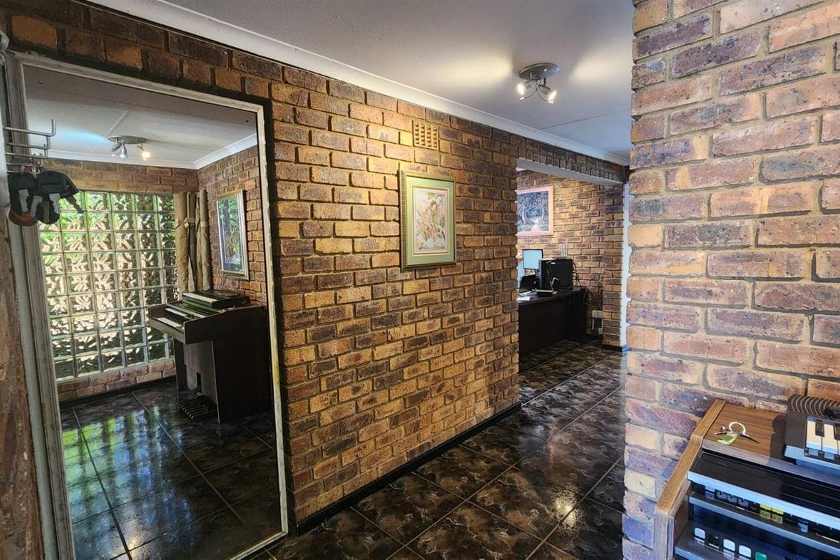 Interior view featuring exposed brick walls, dark tiled flooring, and a glass block feature wall, creating a rustic and textured living space.