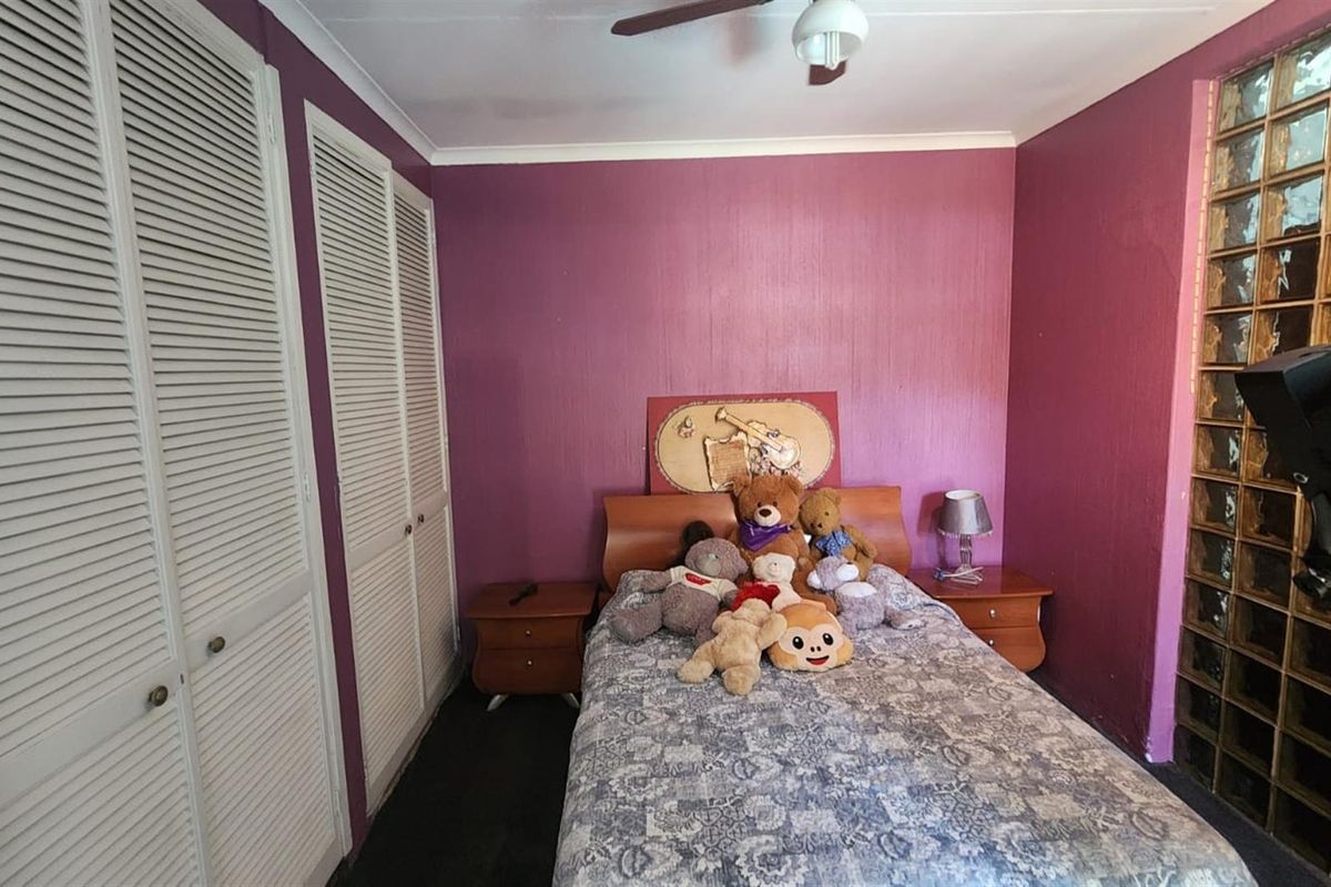 A bedroom featuring built-in louvered door closets, a glass block feature wall, and a ceiling fan.