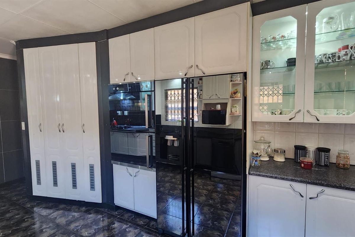 A functional kitchen featuring white cabinetry, dark granite countertops, integrated storage, and tiled flooring with a modern contrast design.