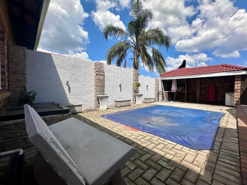 Outdoor pool area featuring a paved patio, built-in braai, and a boundary wall, providing a functional space for outdoor entertainment.