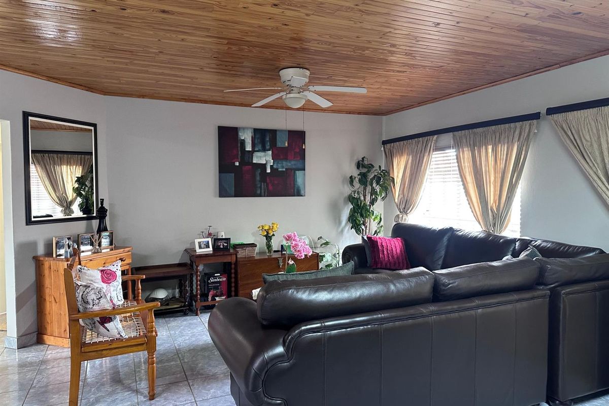 A comfortable living room featuring a warm timber tongue and groove ceiling, ceiling fan, and neutral tiled flooring, offering a cozy and inviting atmosphere.