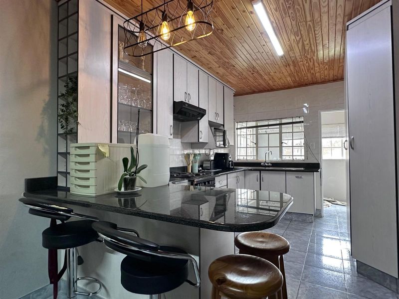 A functional kitchen featuring granite countertops, ample cabinetry, a breakfast nook, and a distinctive timber ceiling, offering a practical layout for daily use.