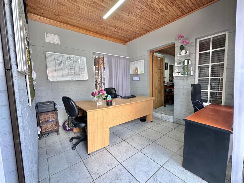 A functional home office featuring painted brick walls, ceramic tiled flooring, and a warm timber tongue and groove ceiling.