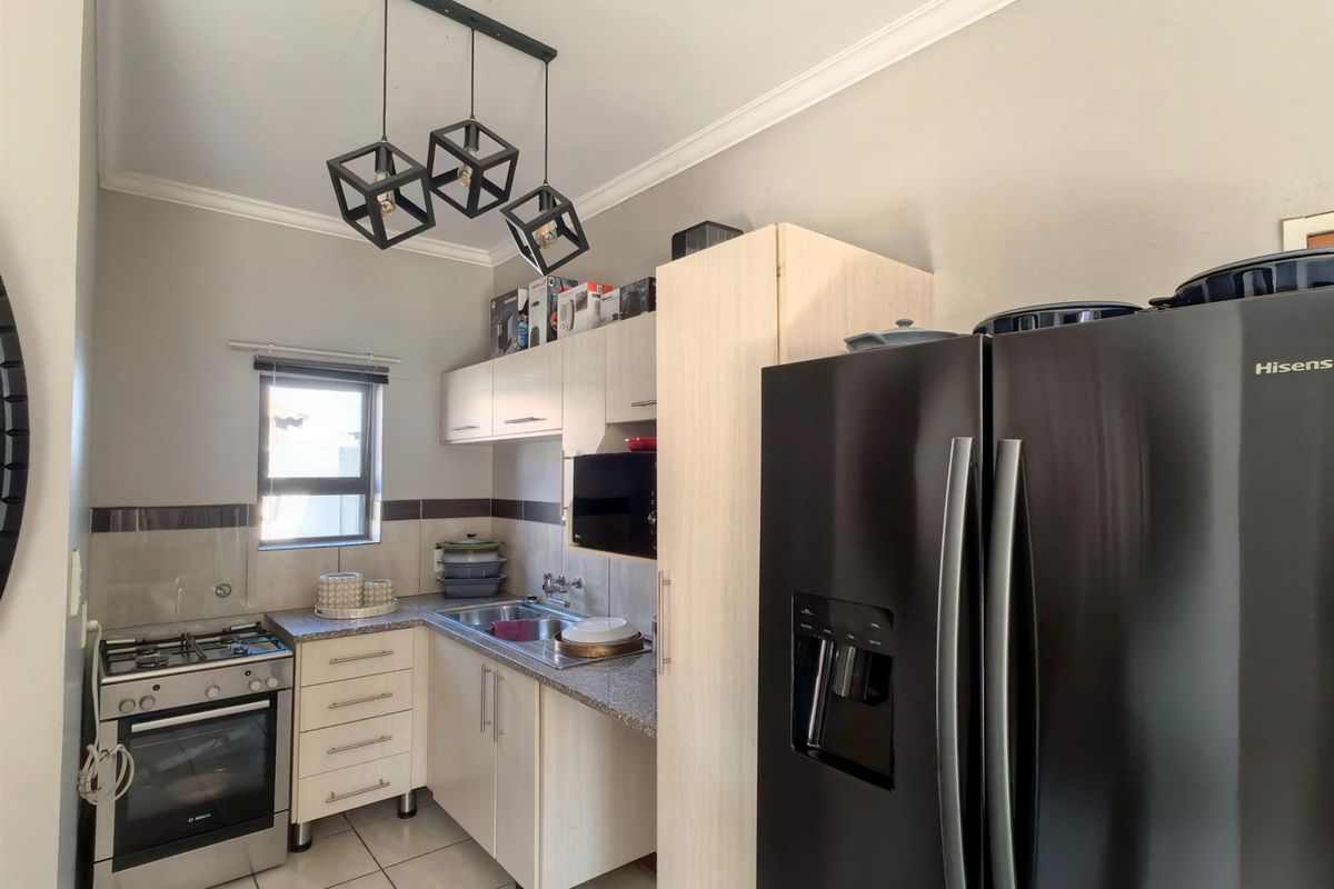 A functional kitchen featuring light-toned cabinetry, granite countertops, a gas stove with oven, and tiled flooring, complemented by modern pendant lighting.