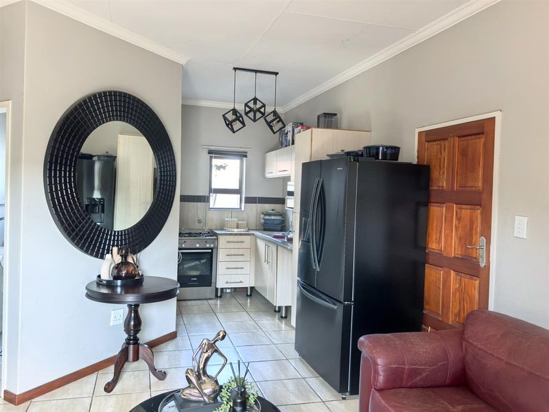 Open plan living area featuring a compact kitchen with built-in cabinetry, gas stove, and tiled flooring, seamlessly connected to the main living space.