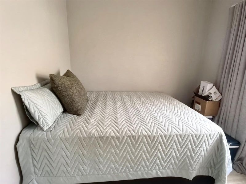 A simple bedroom space featuring neutral wall finishes and window treatments.