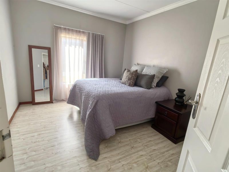 A well-maintained bedroom featuring light-toned laminate flooring, neutral wall finishes, and classic cove cornicing, providing a clean and comfortable living space.