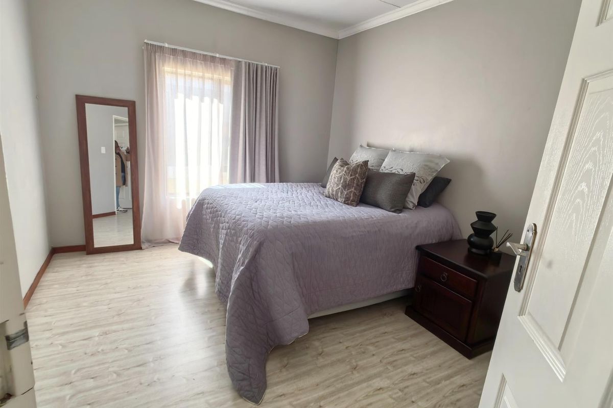 A well-maintained bedroom featuring light-toned laminate flooring, neutral wall finishes, and classic cove cornicing, providing a clean and comfortable living space.