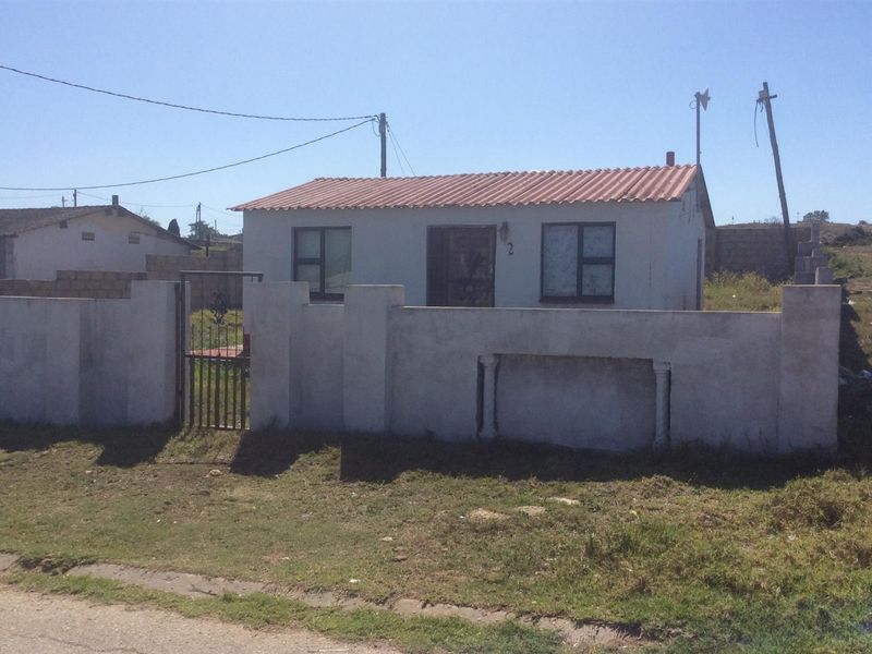 Front view of a single-story detached house featuring a tiled roof, aluminium window frames, and a partially finished perimeter wall with a metal gate.