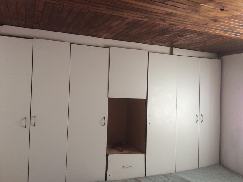 Bedroom featuring extensive built-in white cabinetry and a traditional timber-paneled ceiling.