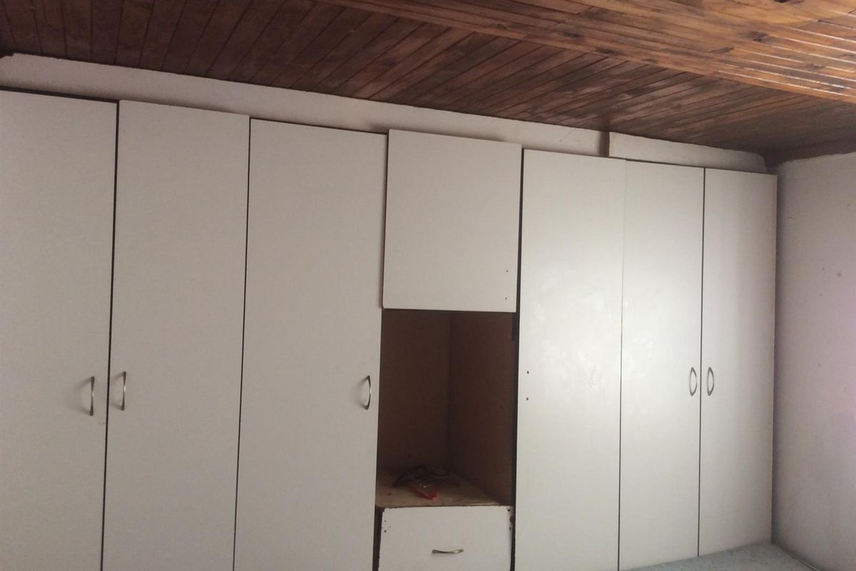 Bedroom featuring extensive built-in white cabinetry and a traditional timber-paneled ceiling.