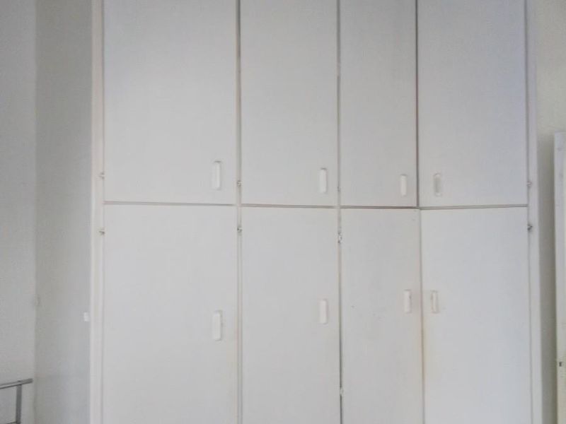 A bedroom featuring floor-to-ceiling built-in cupboards and laminate flooring, offering ample storage space.