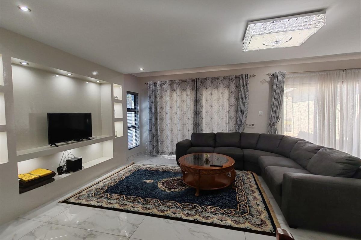 Spacious living room featuring polished marble-look floor tiles, recessed display shelving with integrated lighting, and large sliding doors leading to the exterior.
