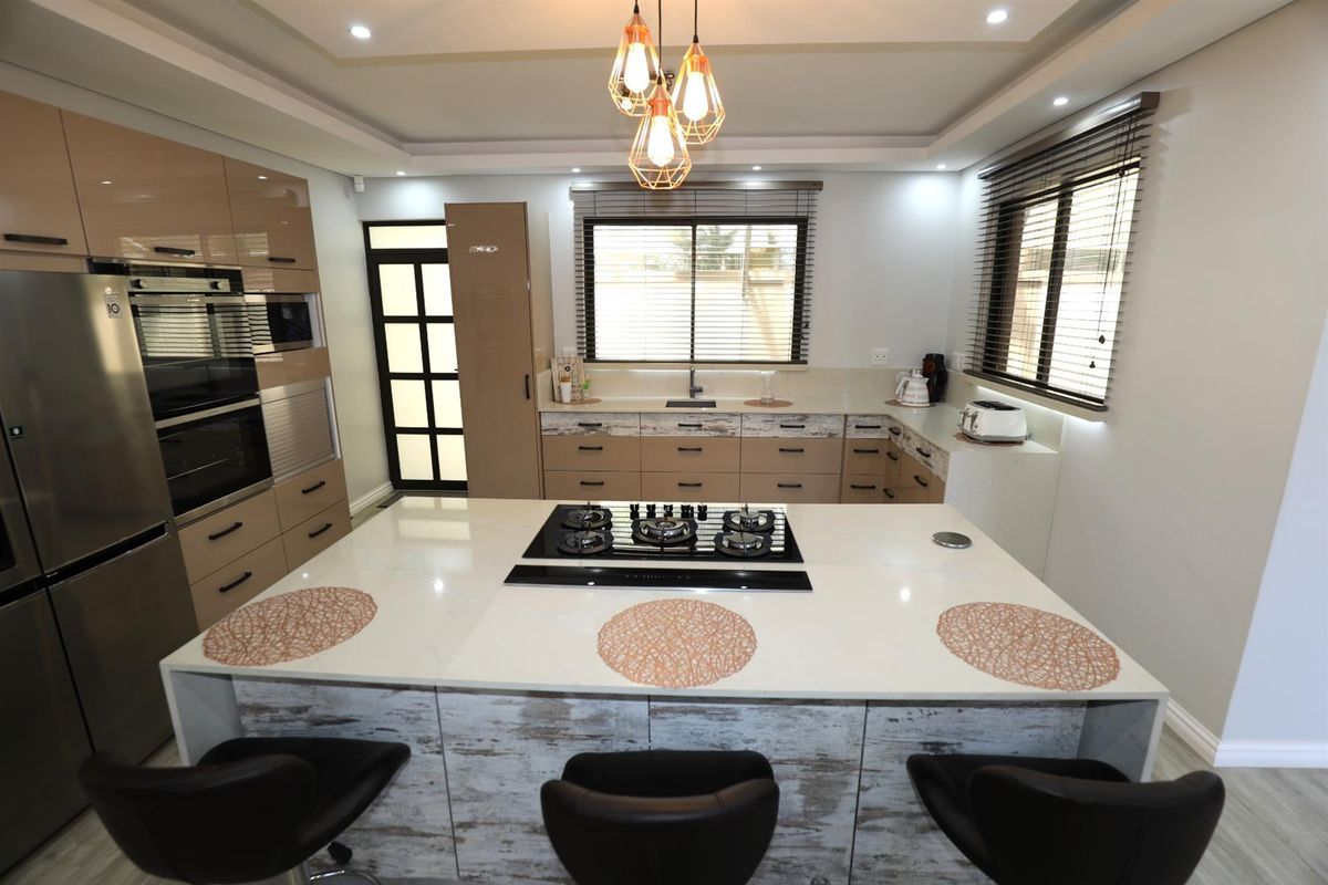 Modern kitchen featuring a large central island with a built-in gas hob, sleek cabinetry, integrated oven, and contemporary pendant lighting.