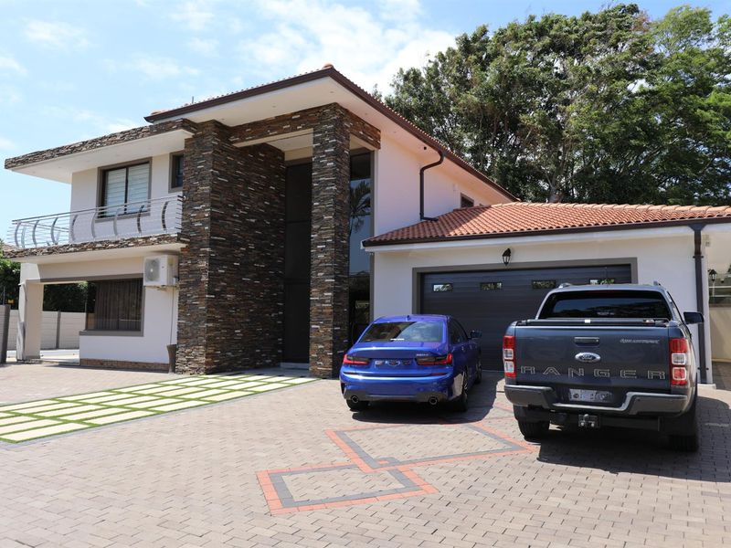 A modern two-story residential property featuring stone-clad pillars, a paved driveway, and an integrated garage.