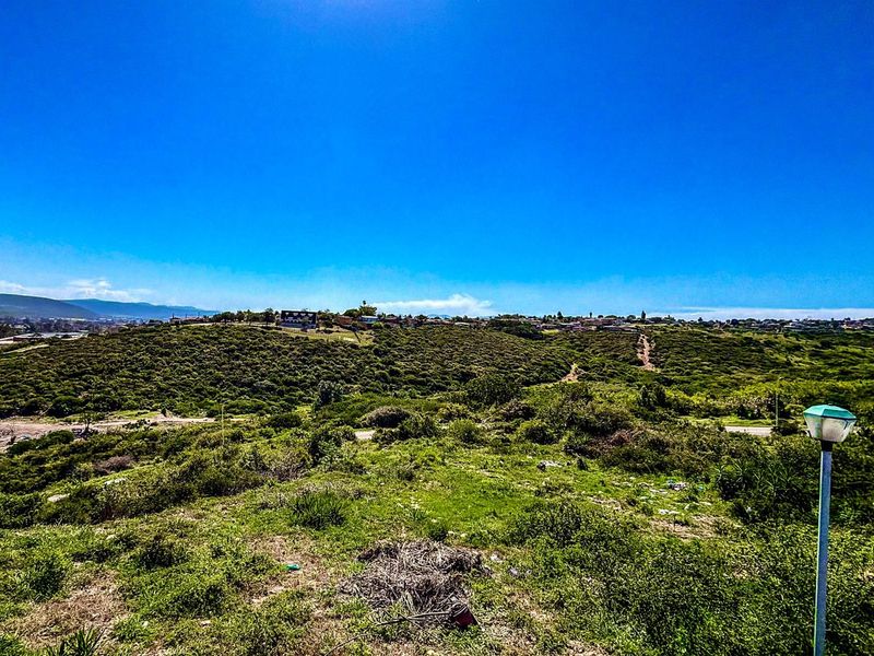 A wide-angle view of the vacant residential land, showcasing the natural landscape, surrounding terrain, and distant neighborhood views.