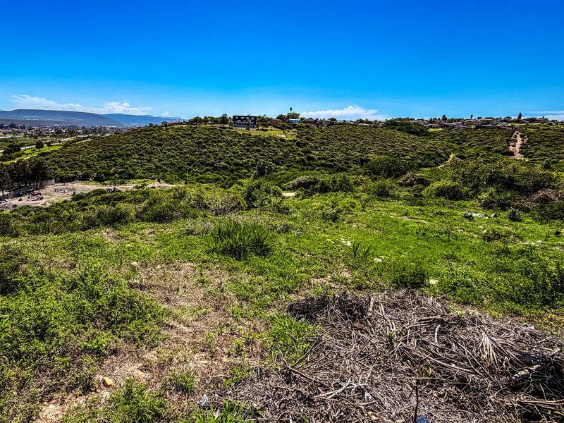 An elevated view of the vacant residential land, showcasing the natural landscape, surrounding hillside terrain, and distant neighborhood views.