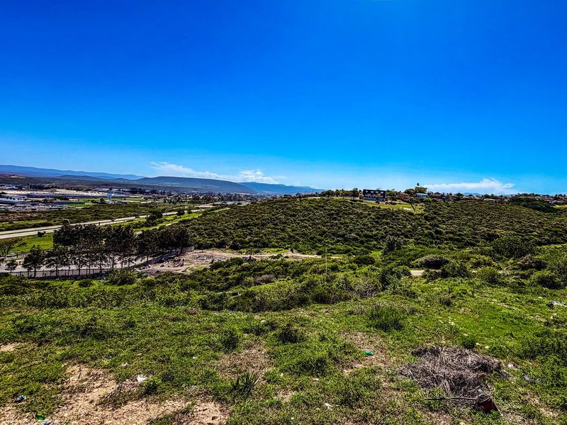 An elevated view of the vacant residential land, showcasing the surrounding landscape, natural vegetation, and distant neighborhood scenery.