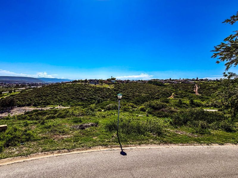 A view of the vacant residential land featuring natural vegetation, rolling hills, and a clear sky, showcasing the property's landscape and surrounding area.