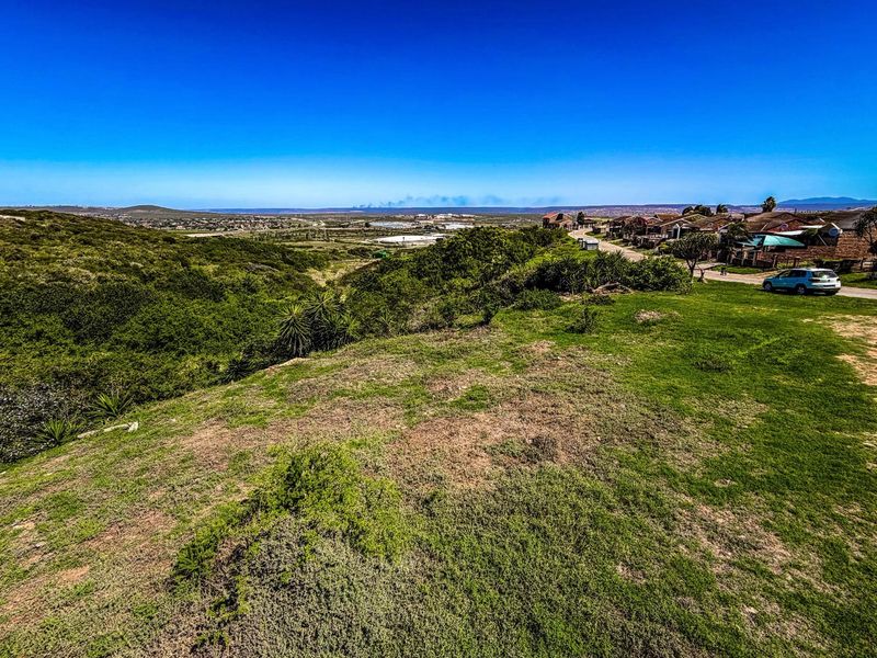 A scenic view overlooking a natural landscape with surrounding residential development and distant horizon.