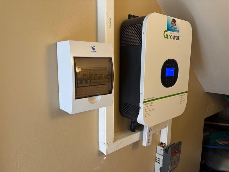Wall-mounted solar inverter system and electrical distribution board with circuit breakers, providing integrated power management infrastructure.