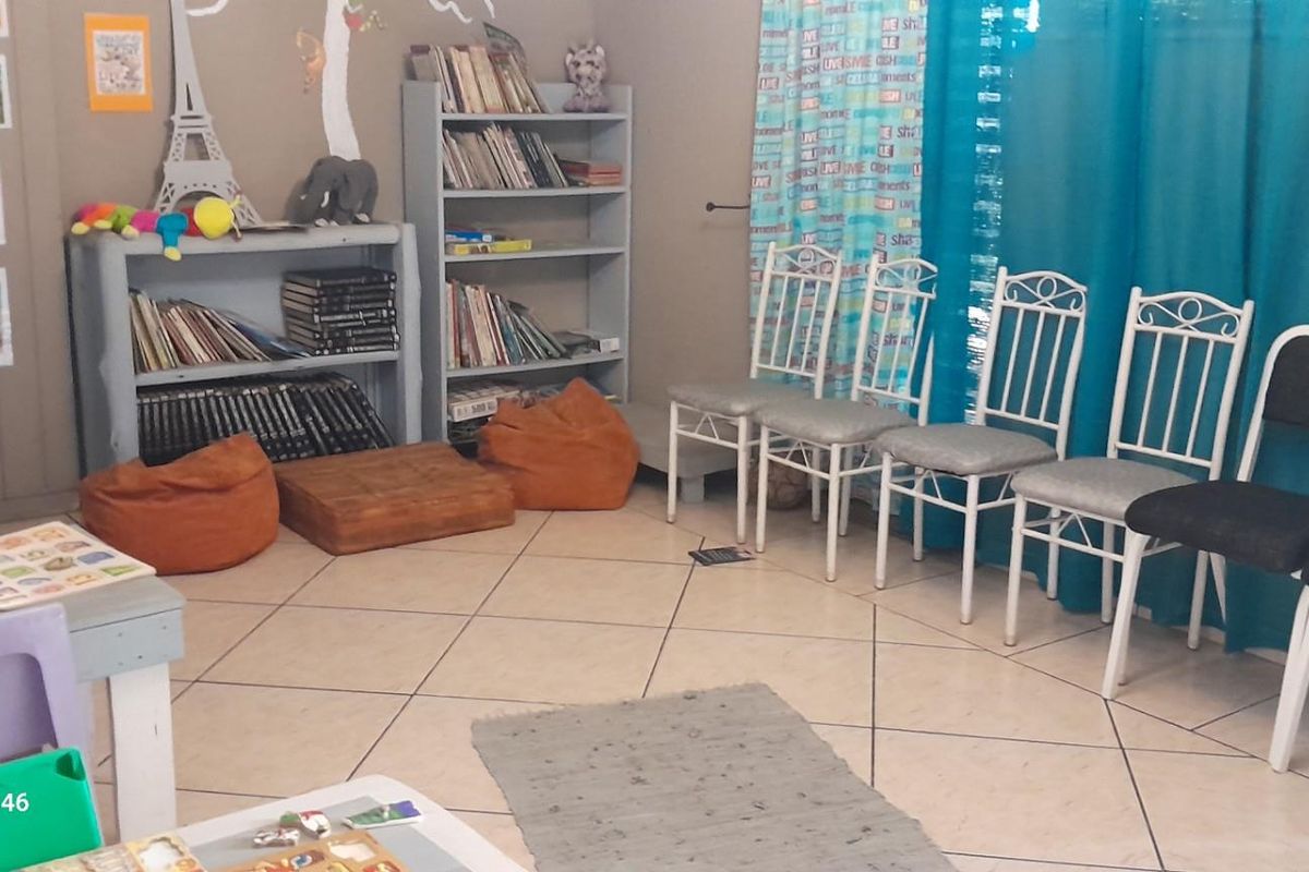 A multi-purpose living area featuring tiled flooring and built-in shelving units, currently utilized as a play or activity space.