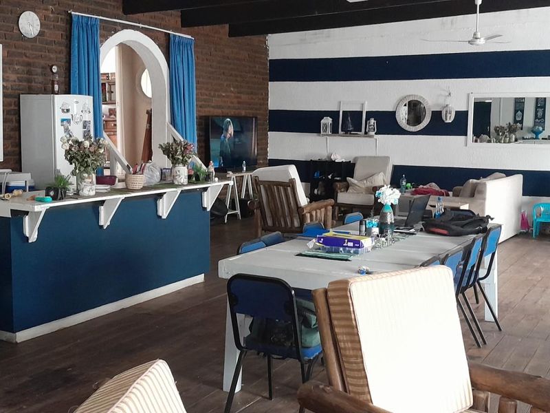 Spacious open-plan living and dining area featuring exposed brickwork, timber flooring, and a central kitchen island with breakfast bar seating.