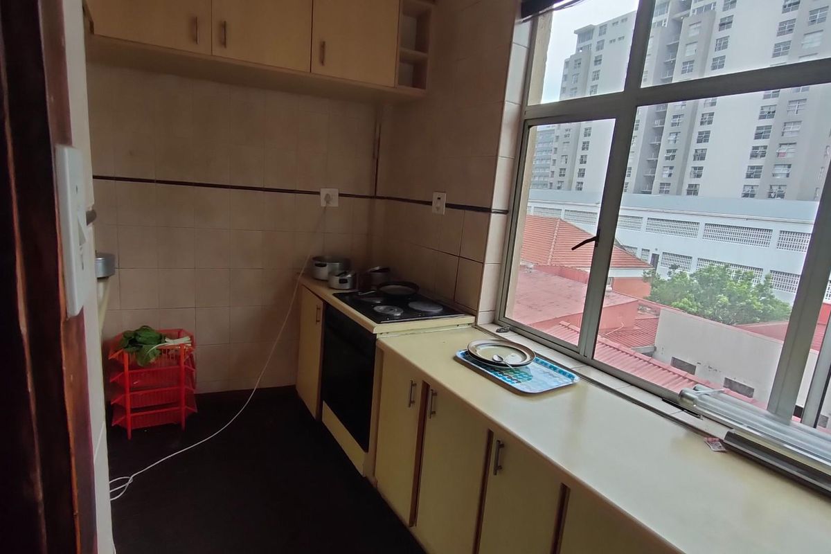 A functional kitchen featuring built-in cabinetry, a stove, and a large window providing natural light and urban views.