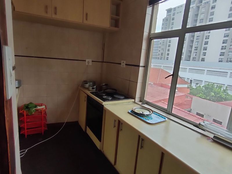 A functional kitchen featuring built-in cabinetry, a stove, and a large window providing natural light and urban views.