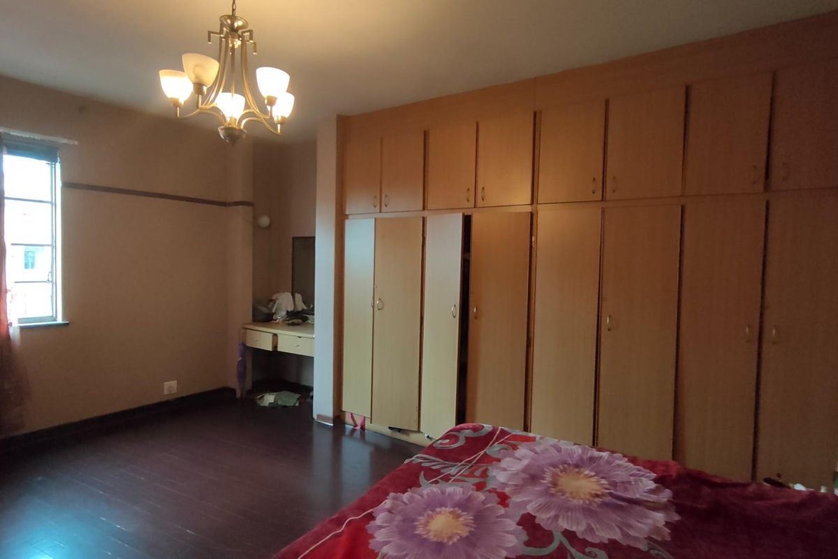 Spacious bedroom featuring extensive built-in wooden cabinetry, dark wood-look flooring, and a classic chandelier fixture.