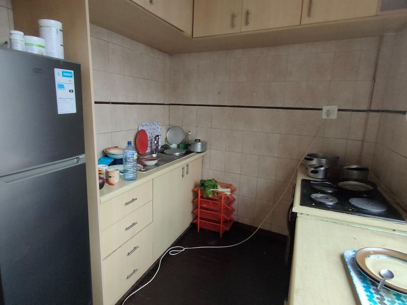 Compact kitchen featuring built-in cabinetry, tiled splashbacks, a fitted hob, and a stainless steel sink.