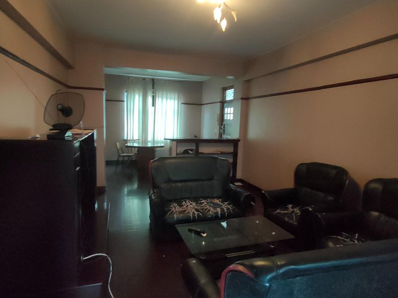 A spacious open-plan living and dining area featuring dark wood-style flooring and neutral wall tones, offering a versatile layout for comfortable living.