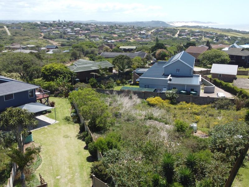 Aerial view of a residential vacant land plot surrounded by established homes and coastal vegetation.