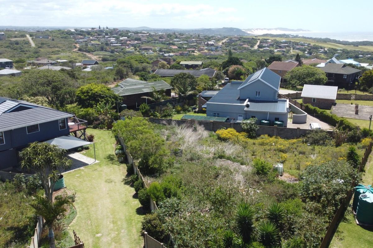 Aerial view of a residential vacant land plot surrounded by established homes and coastal vegetation.