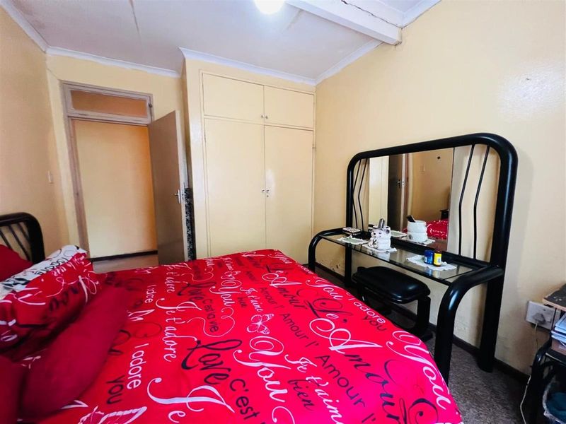 A bedroom featuring built-in cupboards and standard door access, requiring cosmetic updates to improve the overall finish and appeal.