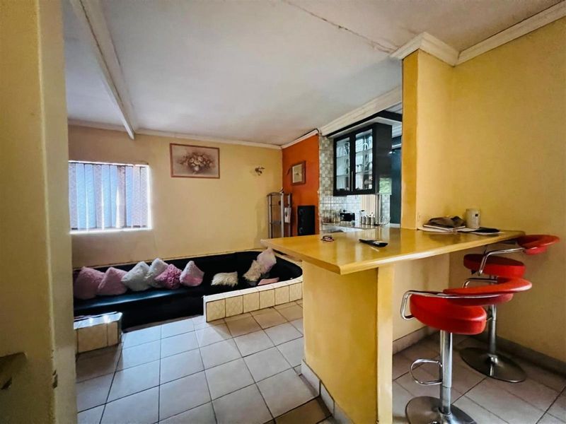 Open plan living area featuring a breakfast bar counter and tiled flooring, adjacent to a compact kitchen space.