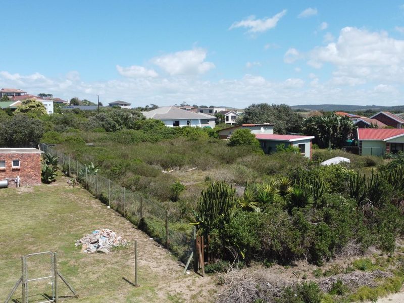 Aerial view of a vacant residential plot featuring overgrown vegetation, perimeter fencing, and a small existing brick outbuilding.