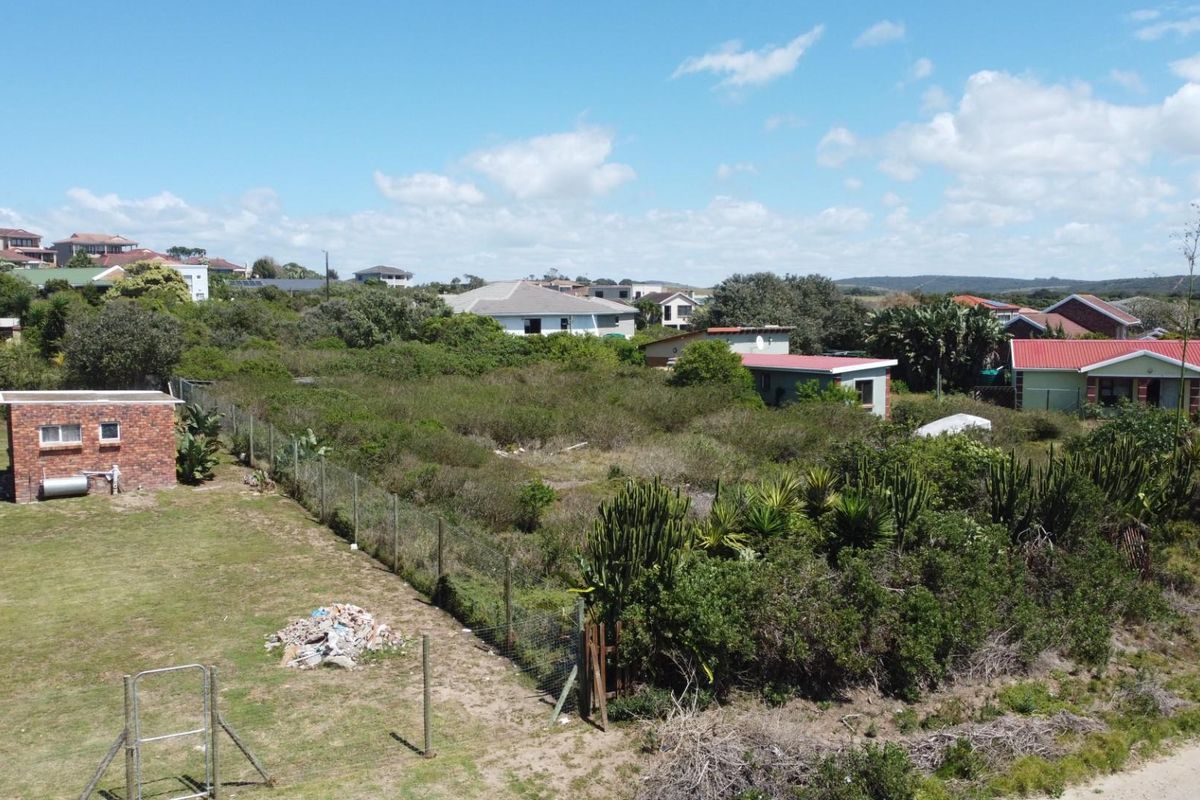 Aerial view of a vacant residential plot featuring overgrown vegetation, perimeter fencing, and a small existing brick outbuilding.