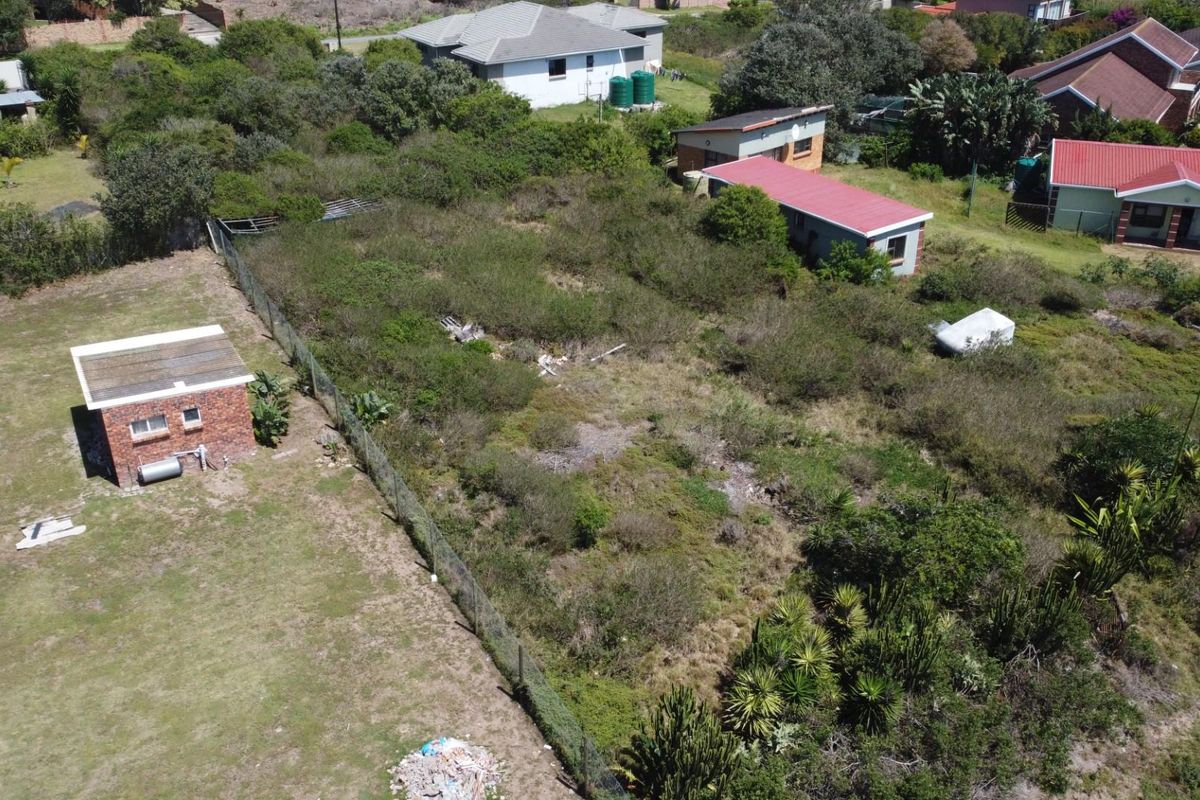 Aerial view of a vacant residential plot featuring established vegetation, a small brick outbuilding, and perimeter fencing in a suburban setting.