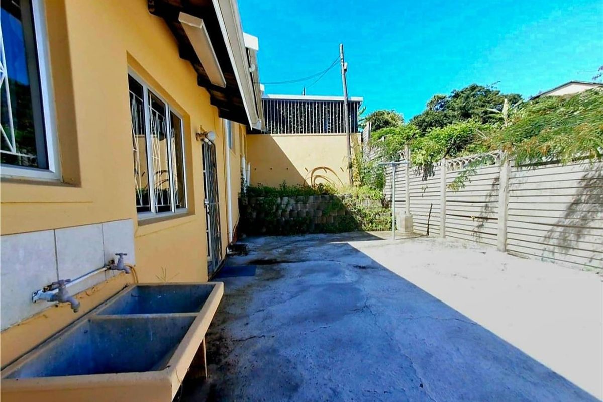 Rear exterior area featuring a concrete wash trough, paved courtyard, and perimeter precast concrete walling.