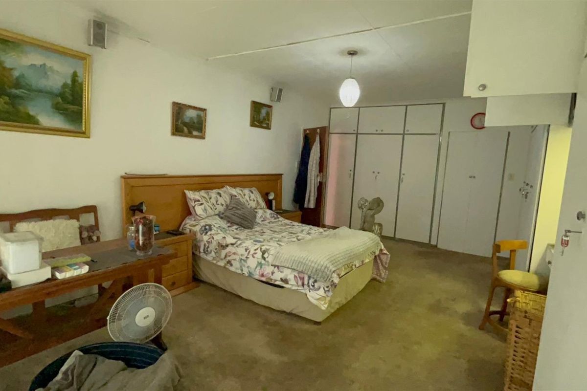 Spacious bedroom featuring built-in cupboards, carpeted flooring, and a neutral layout, offering a functional space ready for modernization.