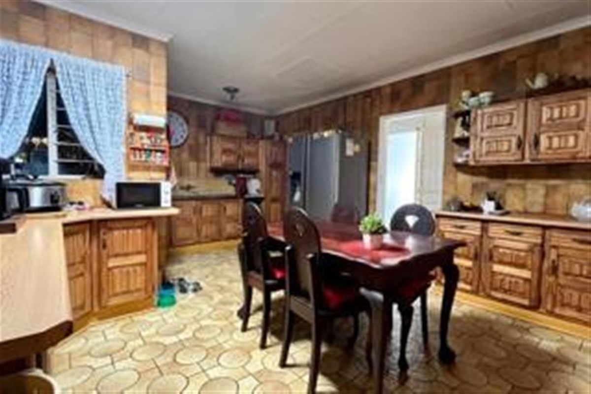 Spacious kitchen featuring extensive wooden cabinetry, tiled flooring, and a dedicated dining area, offering a traditional layout with ample storage space.