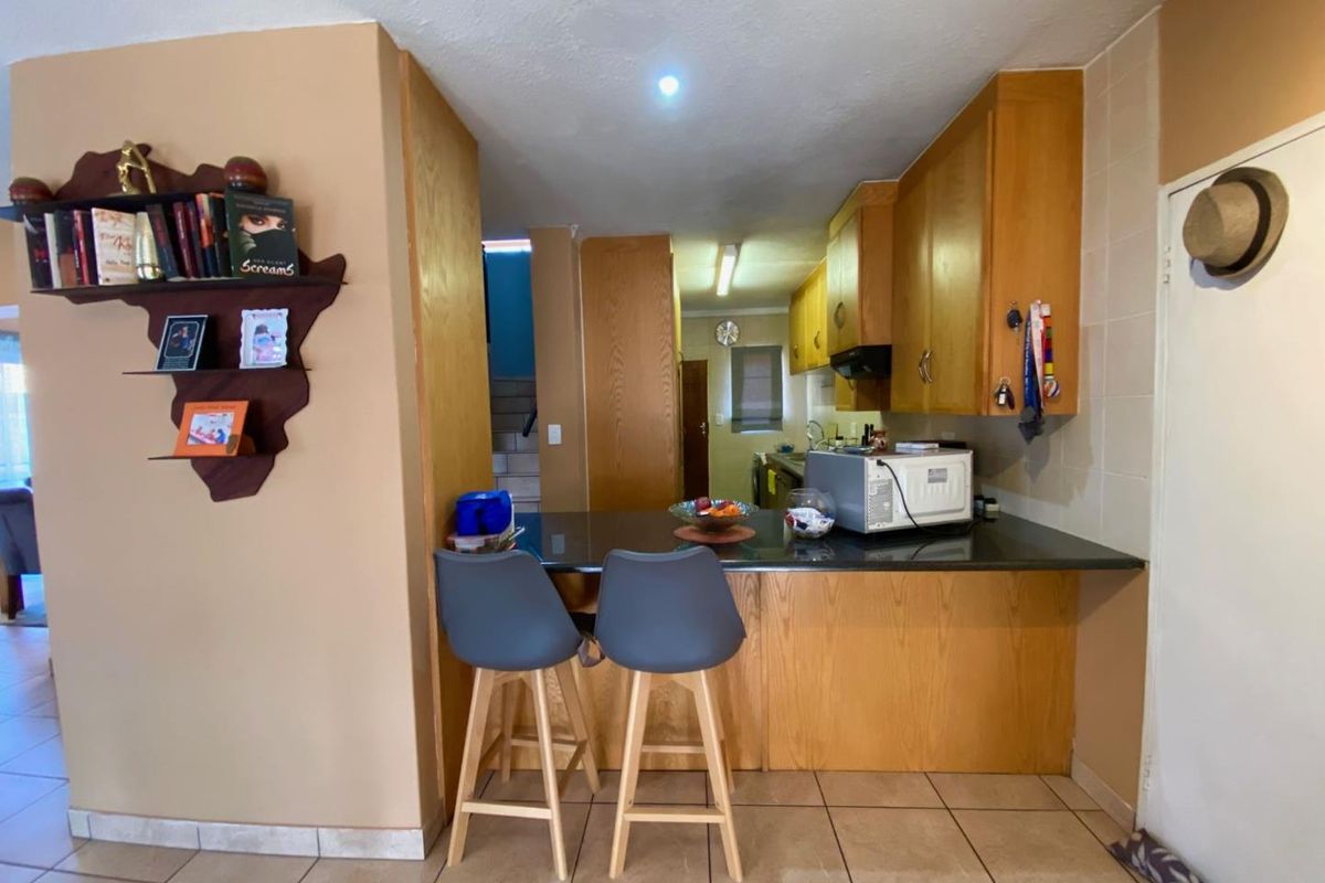 A functional kitchen featuring wooden cabinetry, a dark stone breakfast bar, and tiled flooring, providing a practical layout for daily meal preparation.